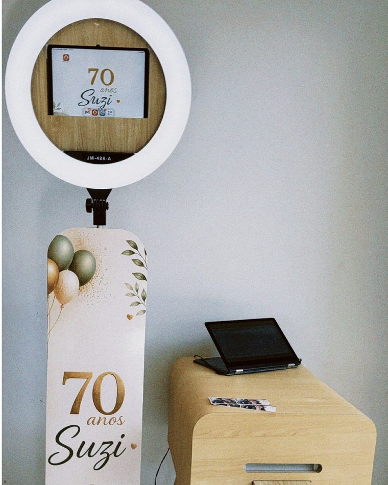 Totem Moderno branco com ring light e arte personalizada de aniversário, ao lado da mesa com a impressora