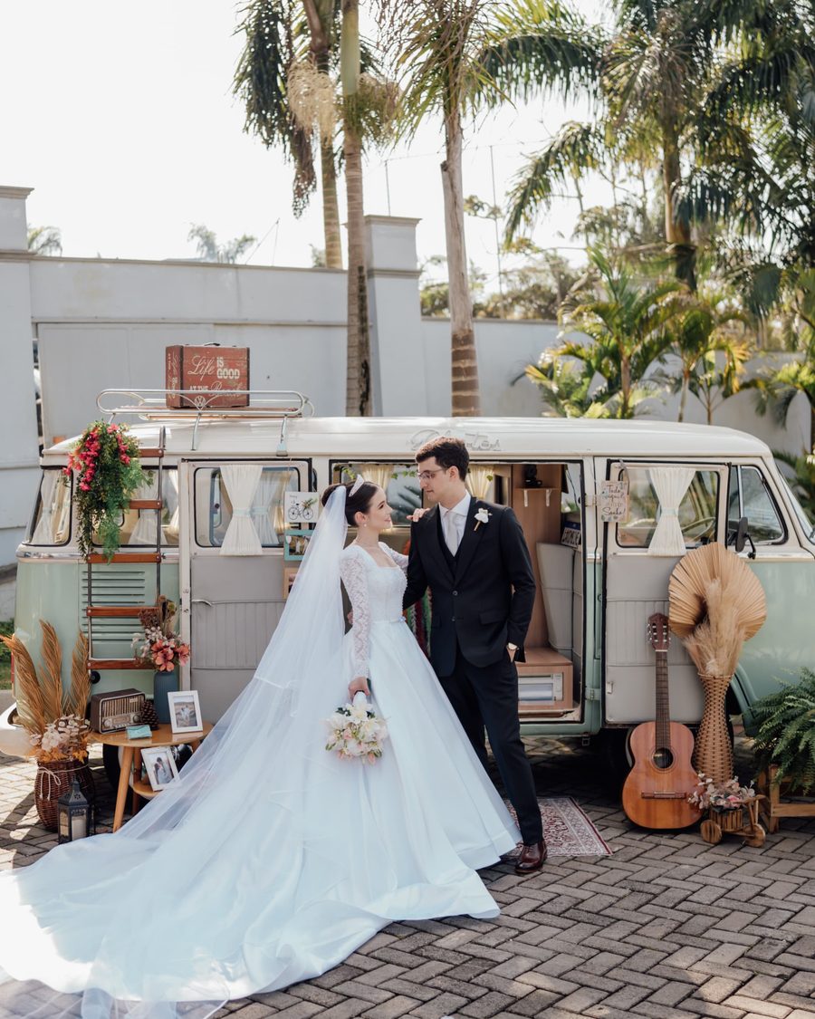 Noivos em frente à Kombi retrô decorada com flores, violão e tapete