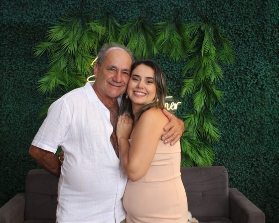Pai e filha abraçados posando na cabine fotográfica da festa