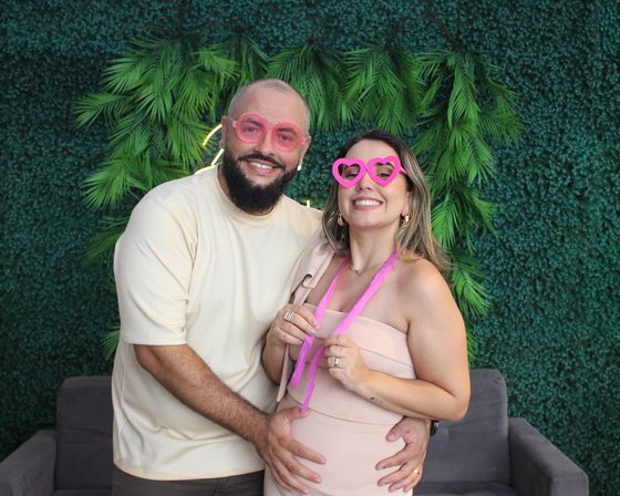Casal de convidados rindo com óculos de coração na cabine fotográfica